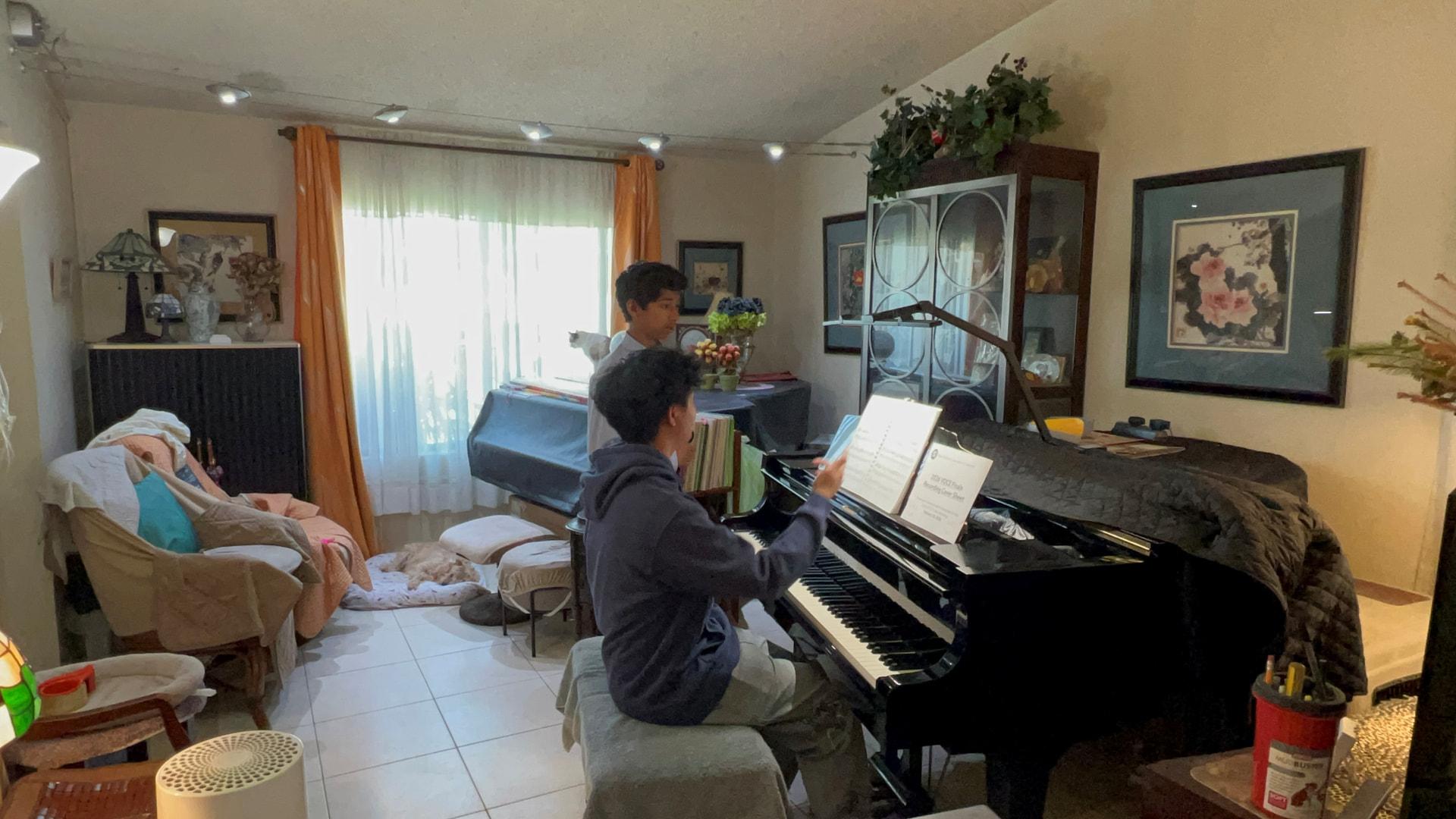 Brendan Li guiding a student through a piece at the grand piano